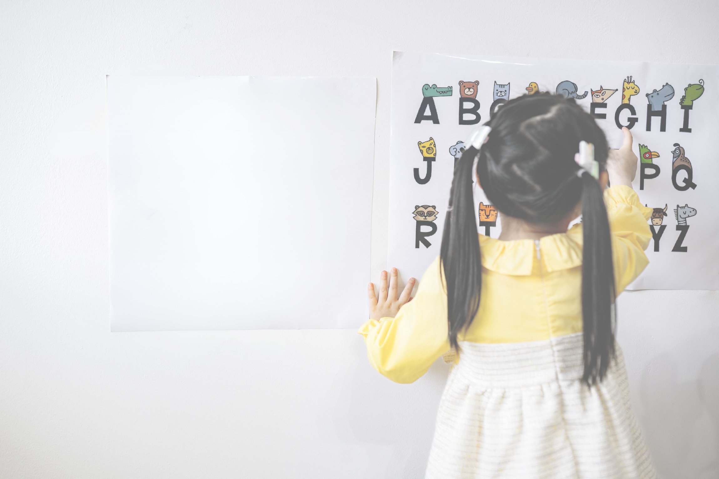 Woman in Yellow Long Sleeve Shirt Standing in Front of White Wall With Assorted Stickers